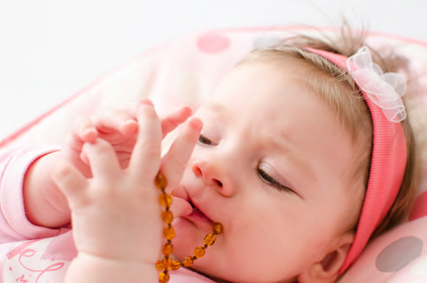 baby holding amber necklace