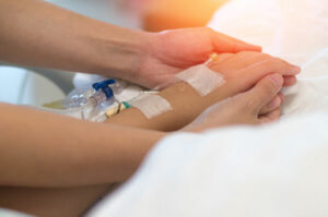Close-up of a patient's hand with an intravenous (IV) line in a hospital setting.